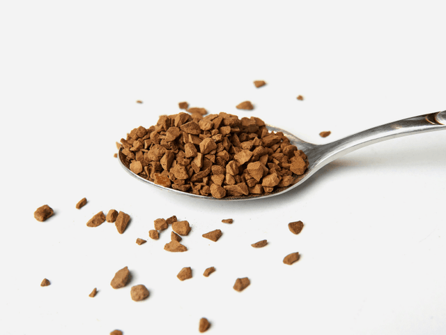 Spoonful of instant coffee grounds on a white background